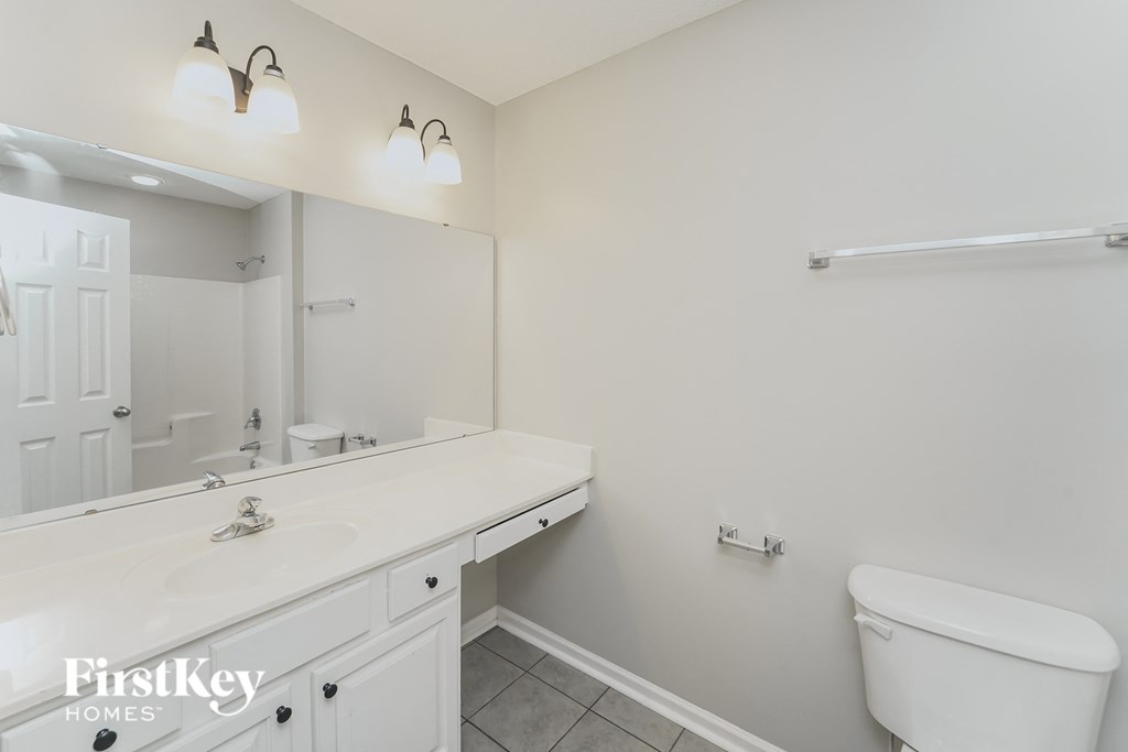 a white bathroom with a large mirror and a toilet and sink