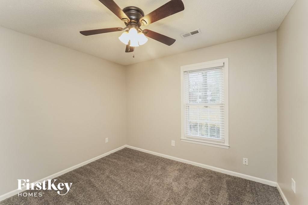 the upstairs bedroom has a ceiling fan and carpet