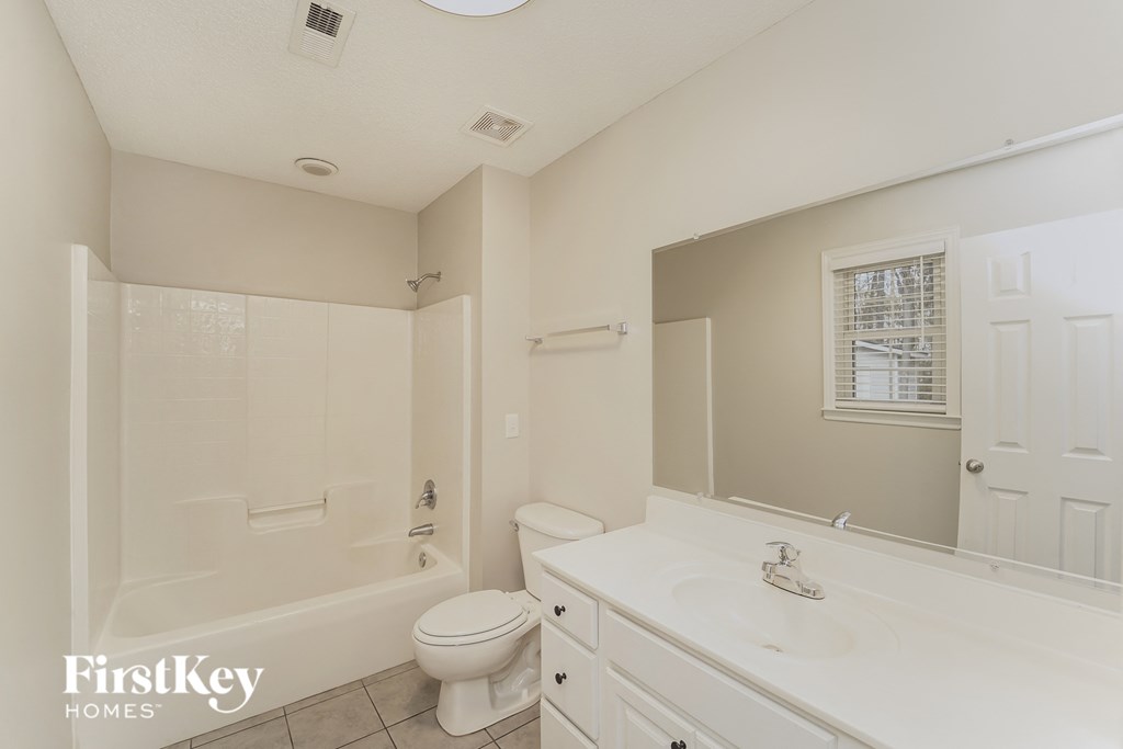 a bathroom with a toilet sink and tub and a mirror