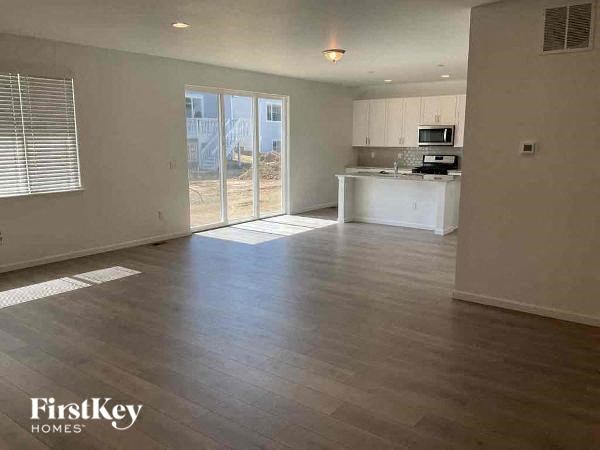 an empty living room and kitchen with wood floors