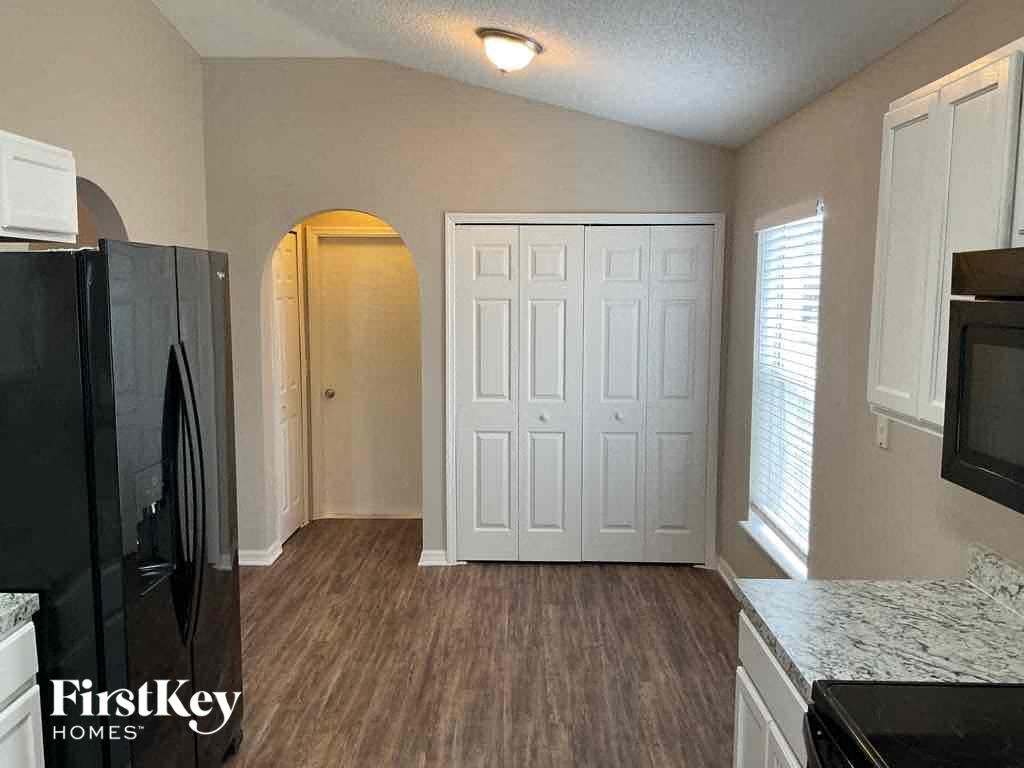 an empty kitchen with a black refrigerator and a white door