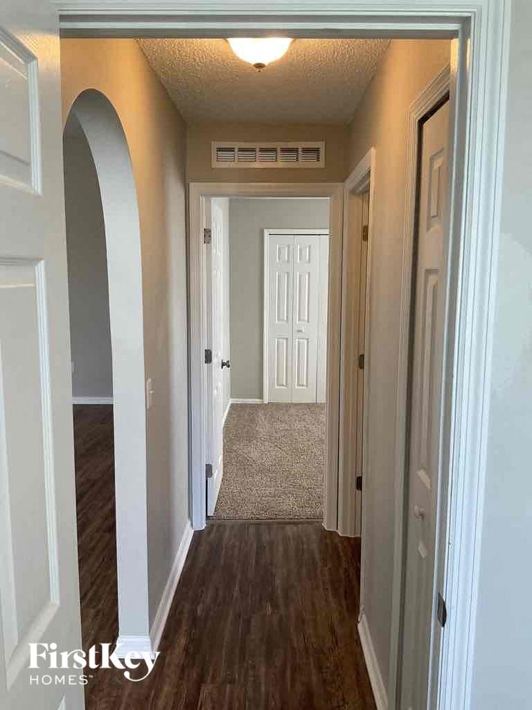 a hallway with a wood floor and white walls and a white door