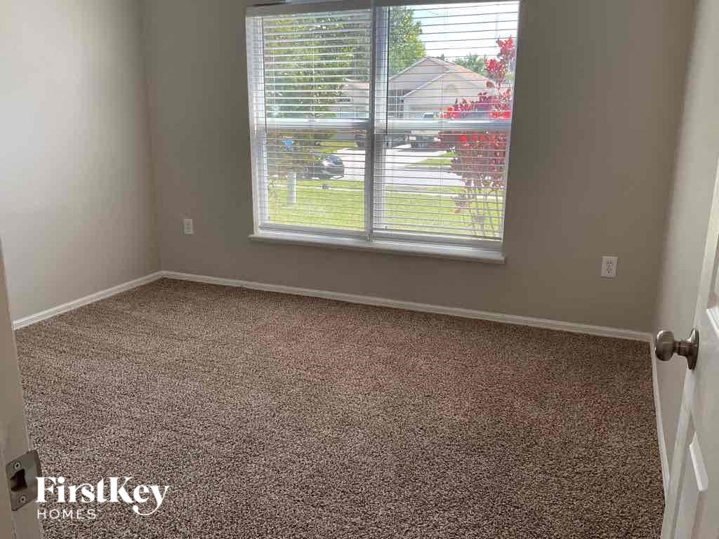 a carpeted room with a window and a white door