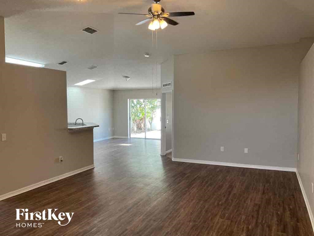 an empty living room with wood floors and a ceiling fan