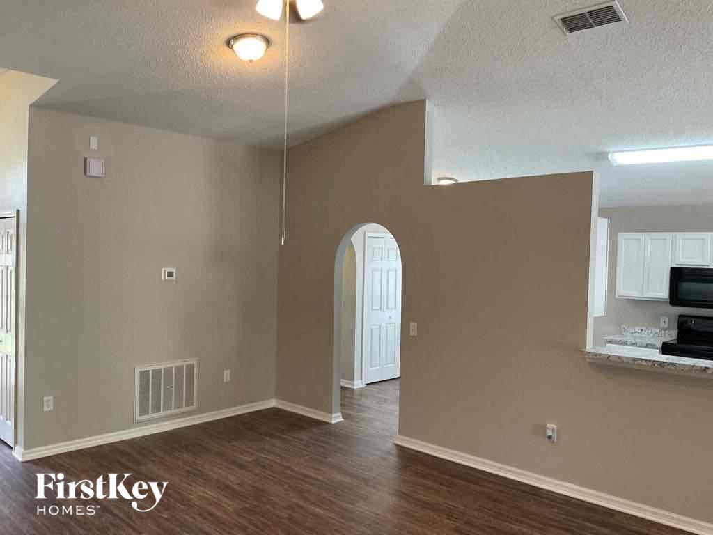 an empty kitchen and living room with wood flooring and a white door