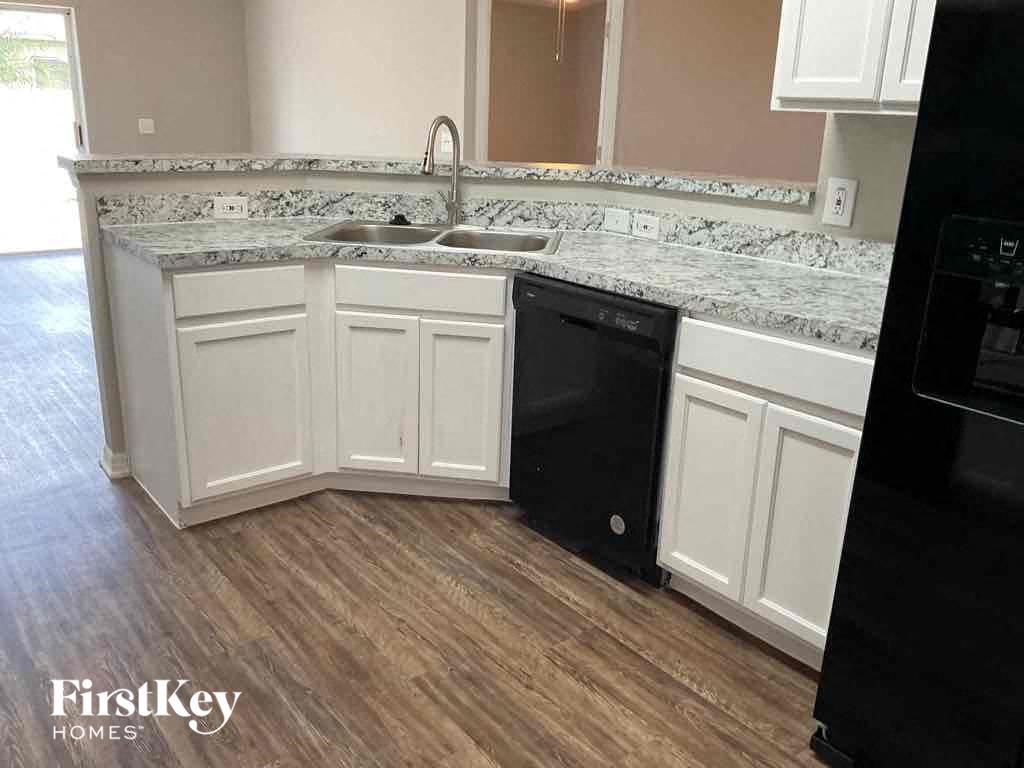a kitchen with white cabinets and a black dishwasher