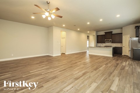 A spacious room with wooden flooring and a ceiling fan.