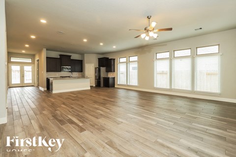 A spacious living room with wooden flooring and a ceiling fan.