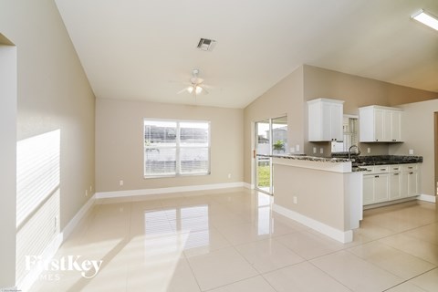 A spacious kitchen and living room with white cabinets and a large window.