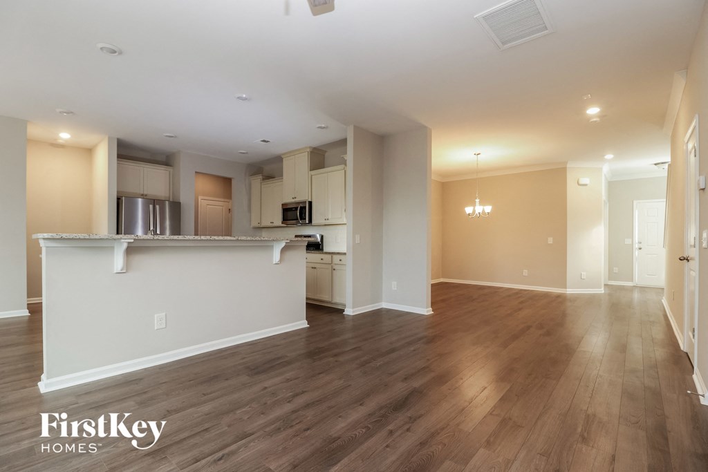 an empty living room and kitchen with wood flooring
