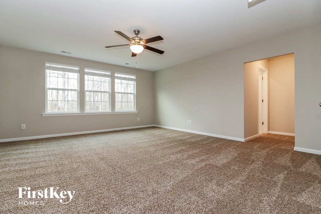 an empty living room with carpet and a ceiling fan