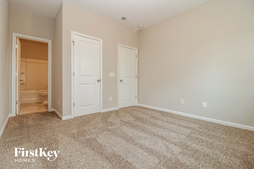 a spacious living room with carpet and a door to the bathroom