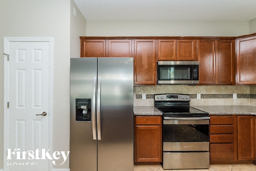 A kitchen with a stainless steel refrigerator, microwave, and oven.