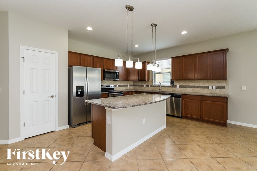 A kitchen with a granite countertop and wooden cabinets.
