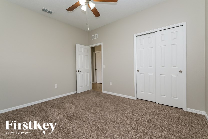 A room with a carpeted floor and a ceiling fan.