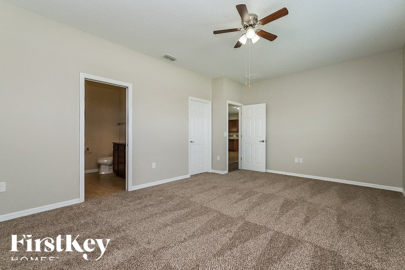 A spacious room with a carpeted floor and a ceiling fan.