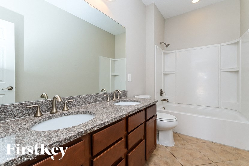 A bathroom with granite countertops and a large mirror.