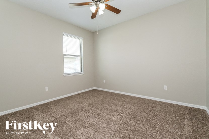 A room with a fan, carpet, and a window.