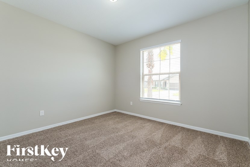 A room with a carpeted floor and a window letting in sunlight.