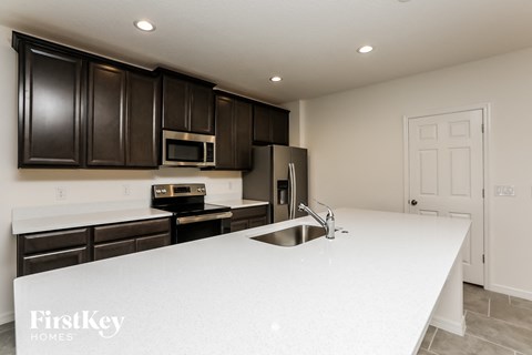 A kitchen with a white counter top and dark brown cabinets.