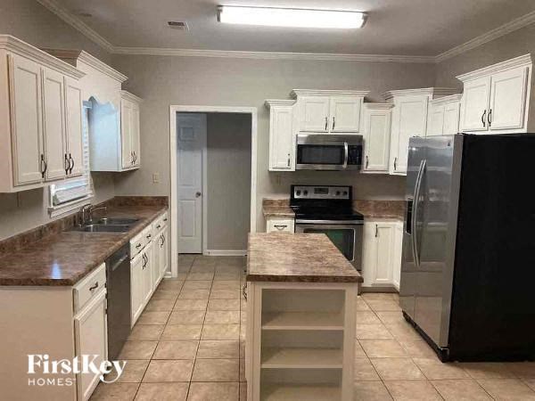 A kitchen with white cabinets and a black refrigerator.
