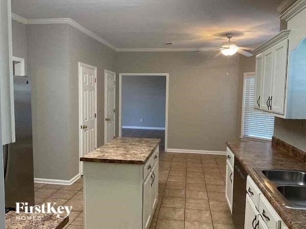 A kitchen with a refrigerator, sink, and cabinets.
