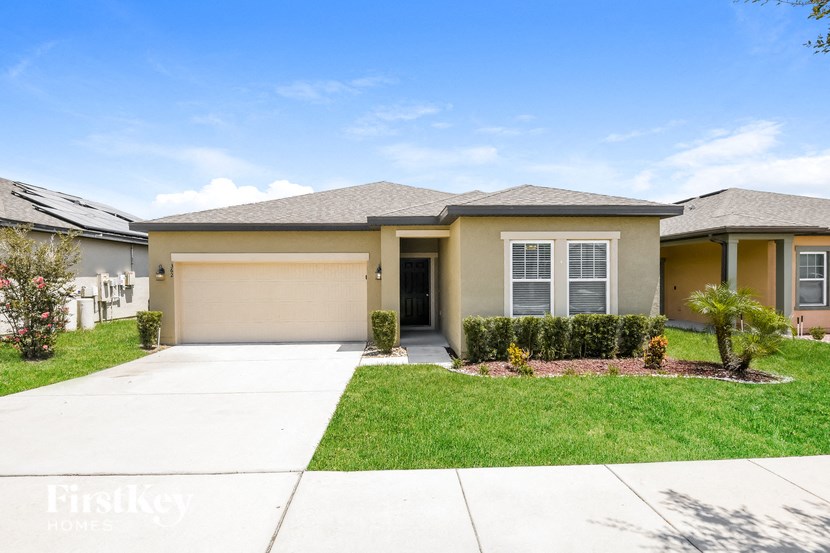 a beige house with a garage door and a lawn