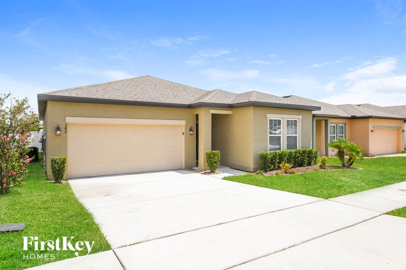 a beige house with a garage door and a lawn