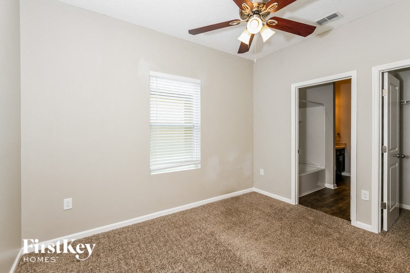 a bedroom with a ceiling fan and a door to a bathroom