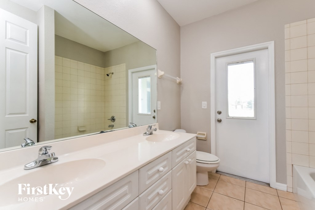 a bathroom with a large mirror and a sink and a toilet