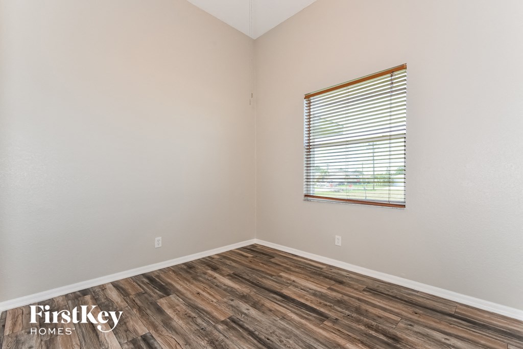the interior of a bedroom with wood flooring and a window