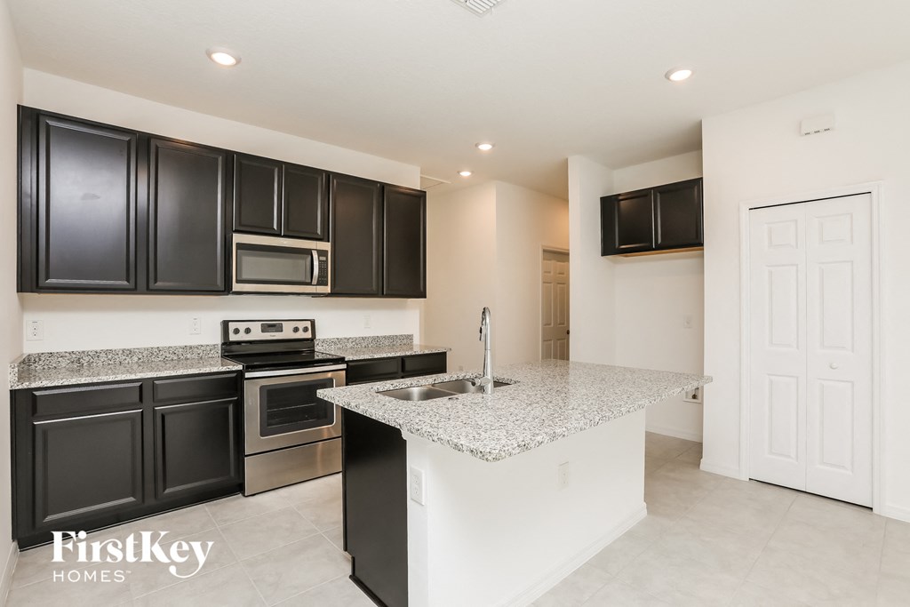 a kitchen with black cabinets and granite counter tops and a sink