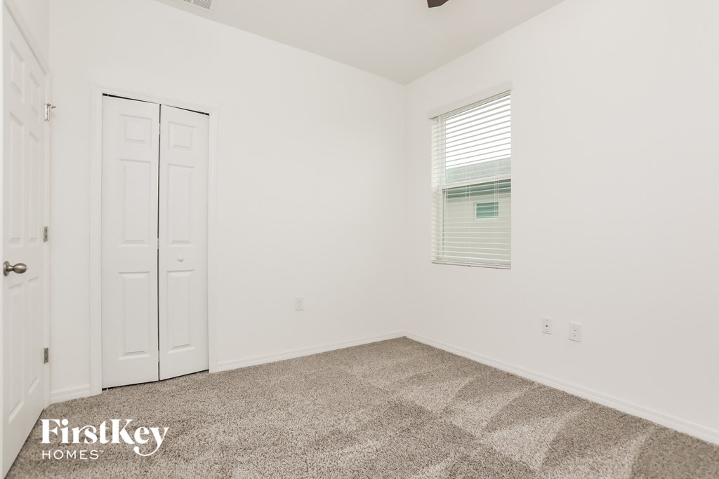 a bedroom with white walls and carpet and a white door and window