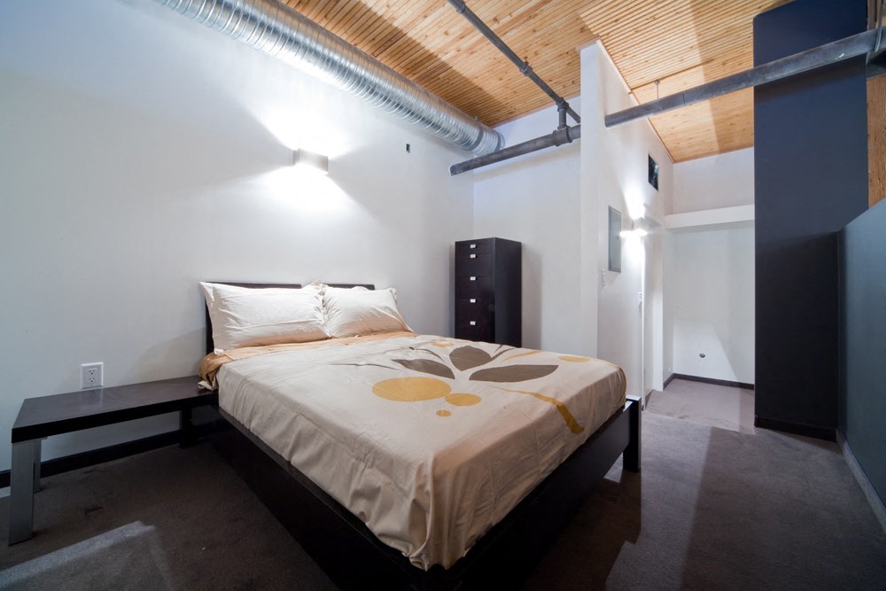 a bedroom with a bed in a room with a wooden ceiling
