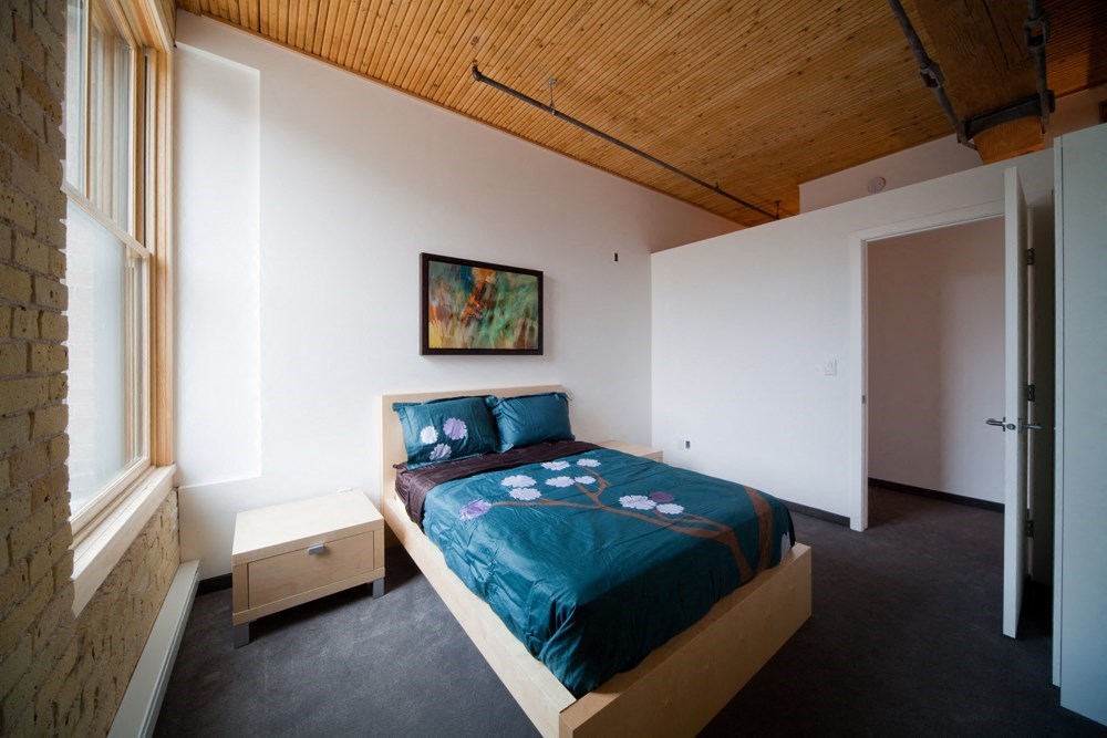 a bedroom with a bed in a room with a wooden ceiling