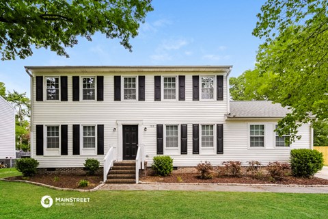 a white house with black shutters and a lawn and trees