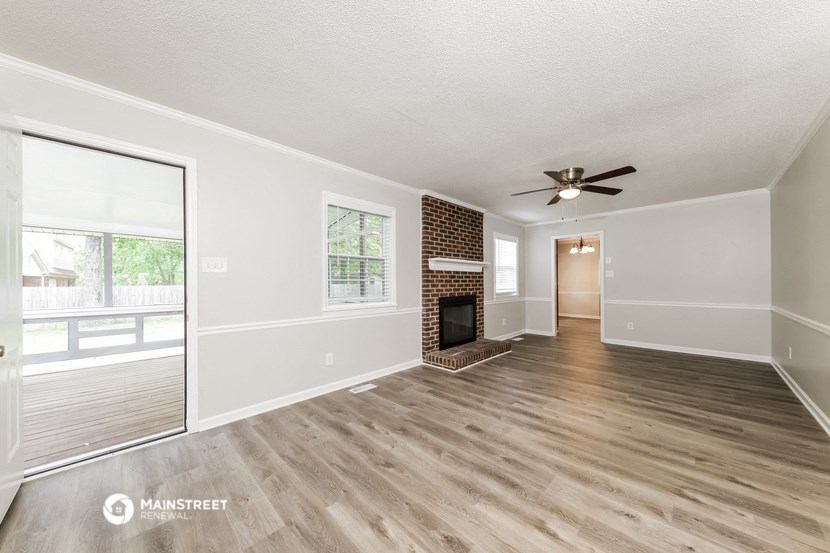 an empty living room with a fireplace and a ceiling fan