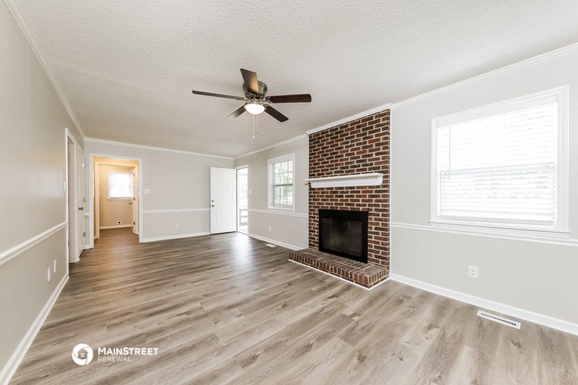 a living room with a brick fireplace and a ceiling fan