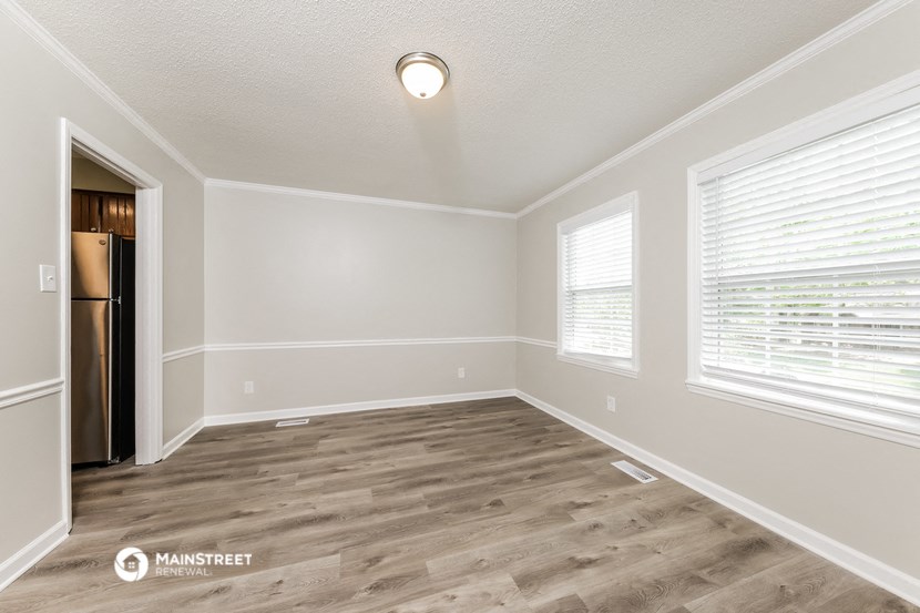 the spacious living room with hardwood flooring and large windows