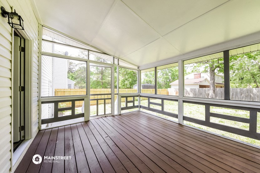 a screened in porch with wood floors and large windows