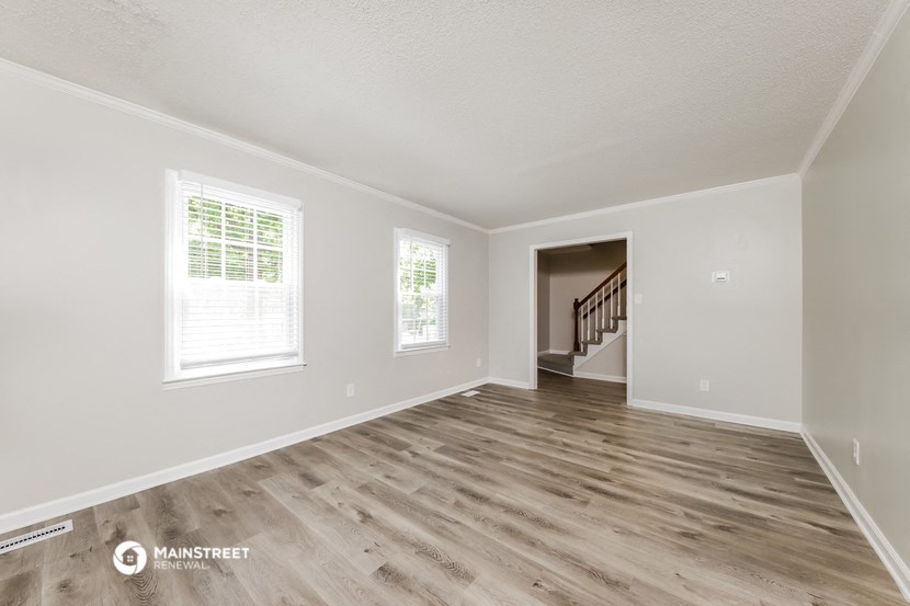 the spacious living room with hardwood floors and white walls