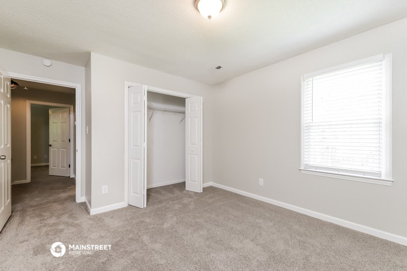 a bedroom with a closet and a window and a carpeted floor