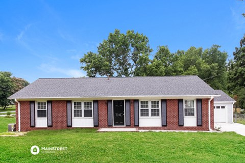 a red brick house with white doors and a green lawn