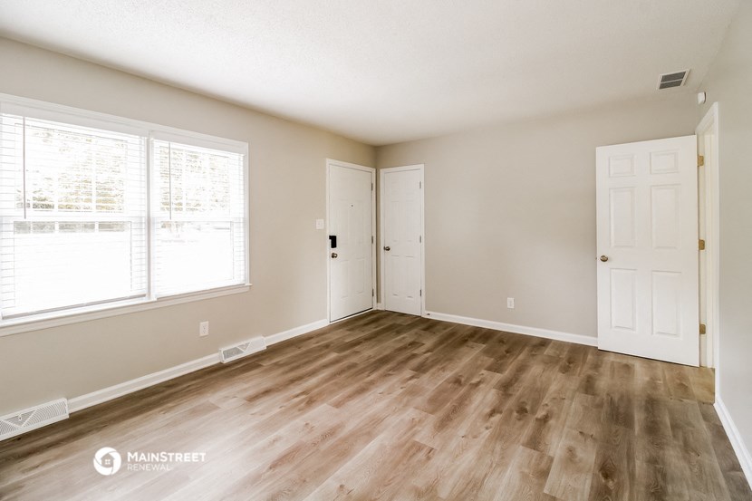 the living room of an empty home with wood flooring