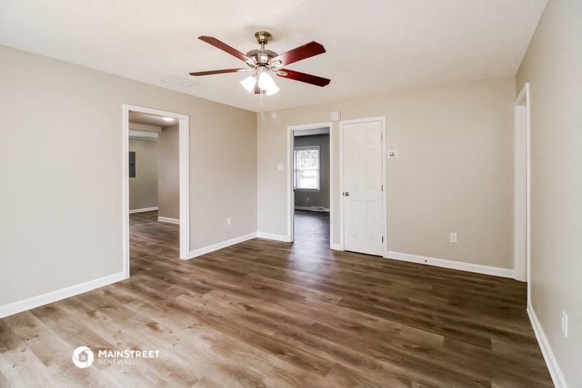 an empty living room with a ceiling fan