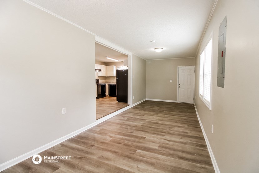 a spacious living room with white walls and wood flooring