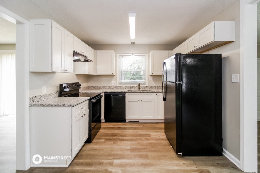 a kitchen with white cabinets and a black refrigerator