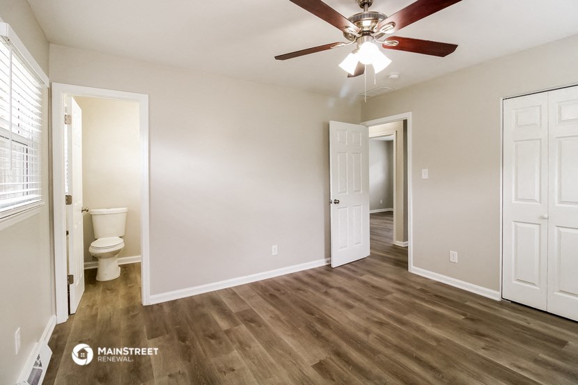 an empty living room with a ceiling fan and a toilet