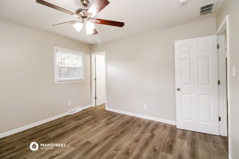 an empty living room with a ceiling fan and a door