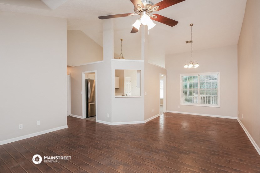 the living room of an empty house with a ceiling fan